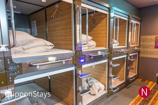 Two tiers of wood-lined sleeping capsules with numbered berths and pull-down screens