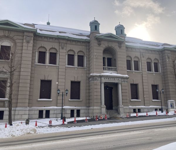 The former Bank of Japan Otaru branch in winter, a grey stone building with twin domes above a snow-lined street