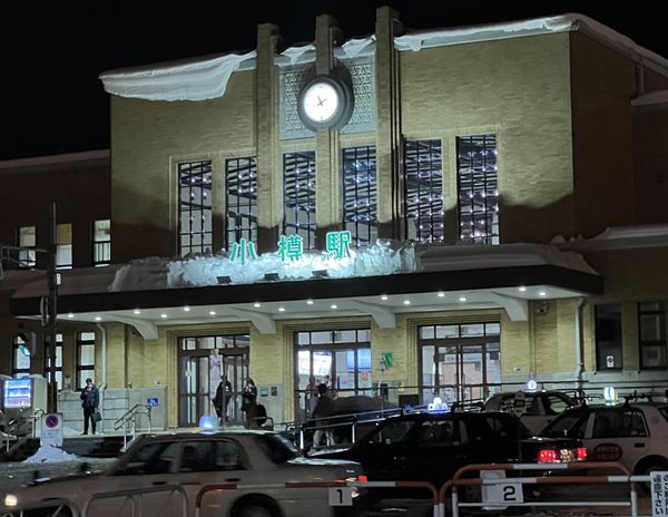 JR Otaru Station lit at night with snow on the roof and taxis waiting at the rank