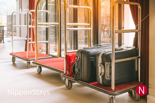 Suitcases on hotel luggage carts in a lobby, ready for transfer between hotels in Japan