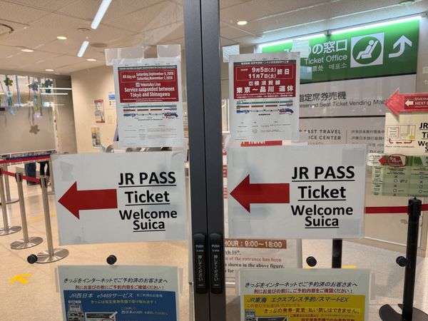 Door signage at the JR EAST Travel Service Center in Shibuya Station, listing JR Pass, tickets and Welcome Suica