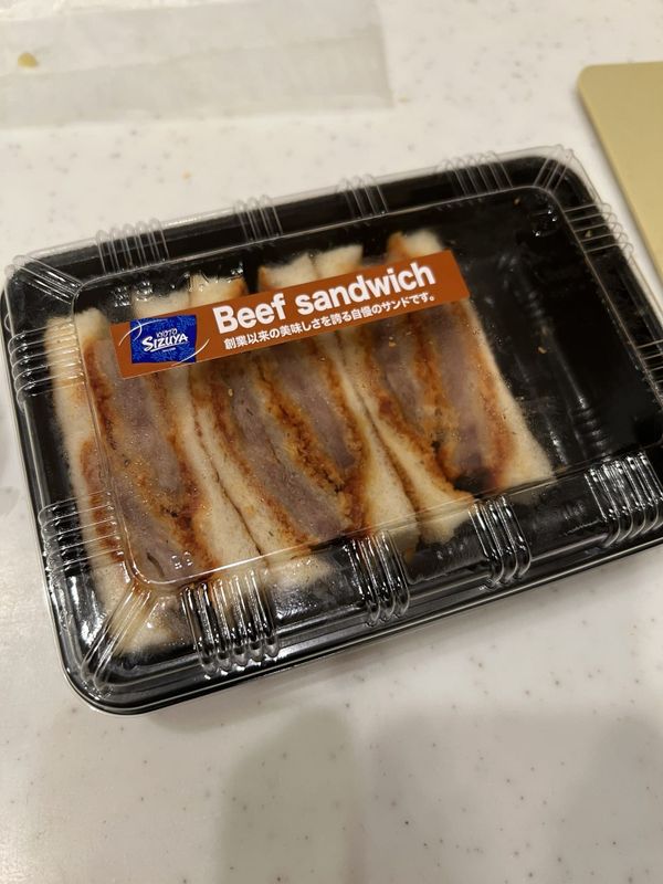 A Kyoto beef katsu sandwich in its takeaway pack, cut into thick slices