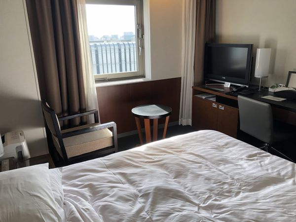 Guest room at Hakata Excel Hotel Tokyu in Fukuoka, with a bed, an armchair, a small round table, a desk and a window
