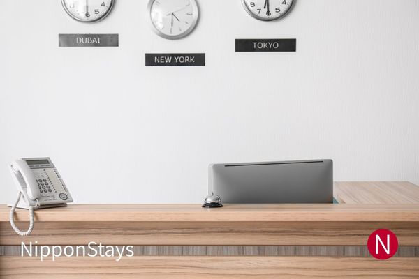 An empty hotel reception desk with a bell and wall clocks for Dubai, New York and Tokyo
