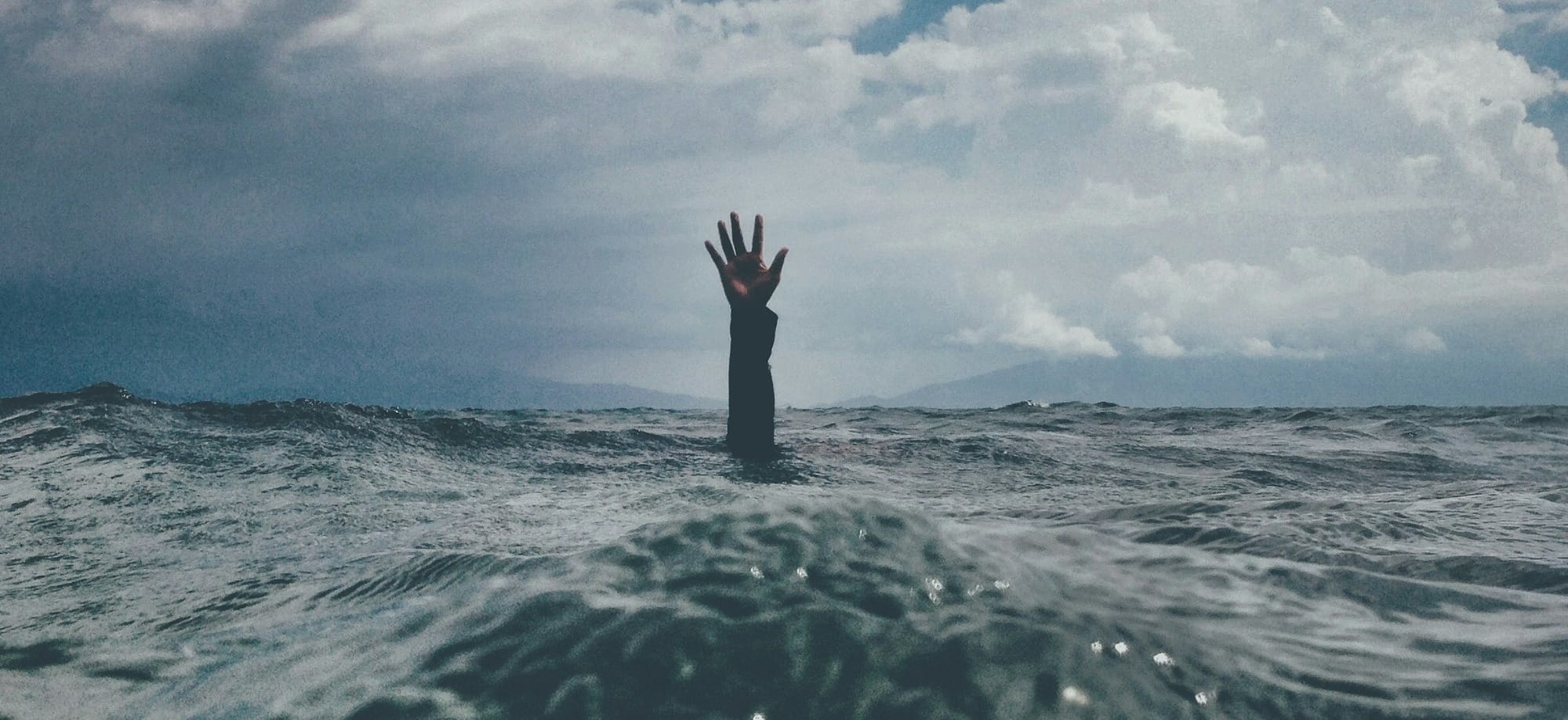 photo of person reach out above the water
