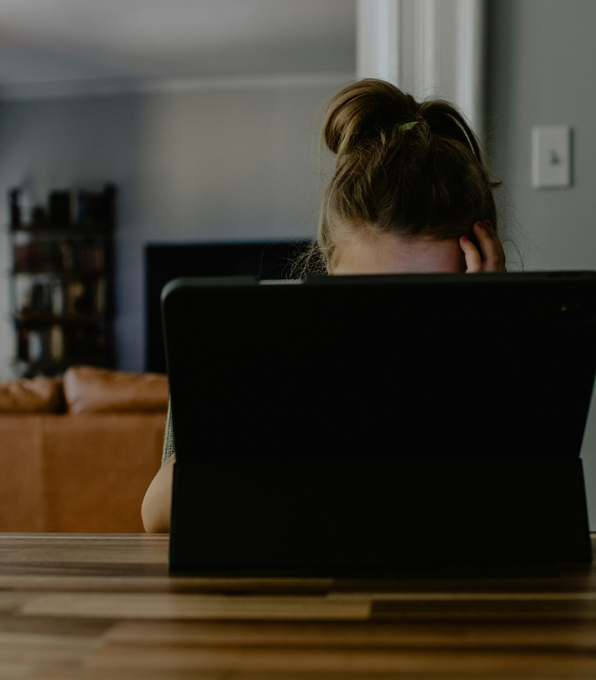 woman in white tank top sitting on chair using black laptop computer