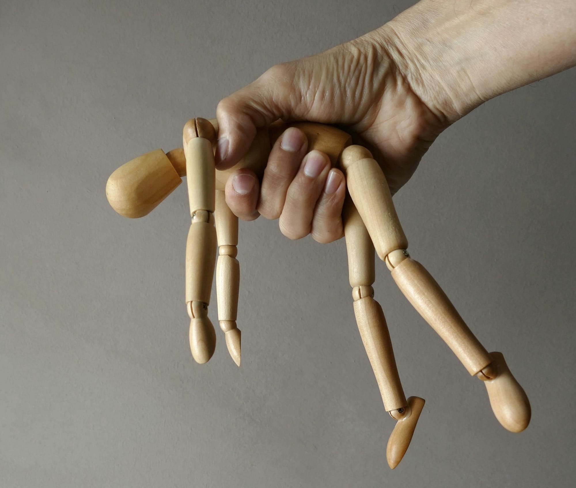person holding brown wooden mannequin
