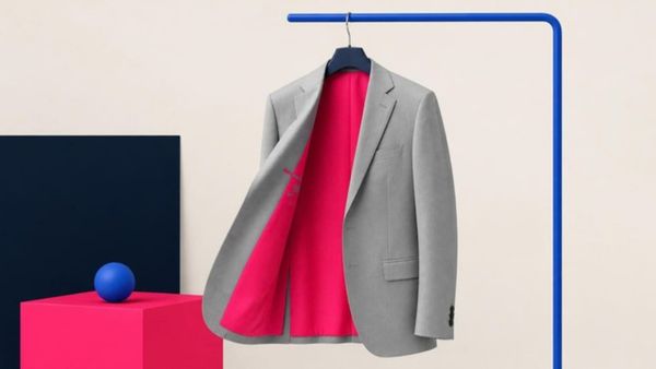 A plain grey suit jacket on a hanger, flipped open to show a bold pink lining.