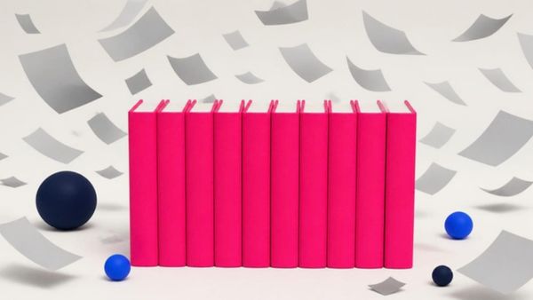 Ten solid pink books stand in a row while loose grey sheets of paper blow away around them.