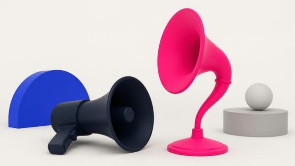 A navy megaphone lies on its side next to an upright pink listening horn.