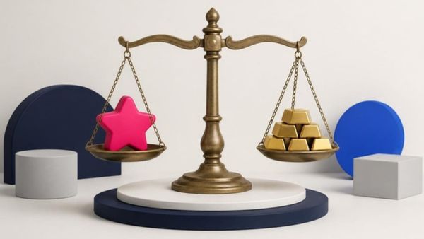 A brass balance scale holds a pink star on one side and gold bars on the other, perfectly level.