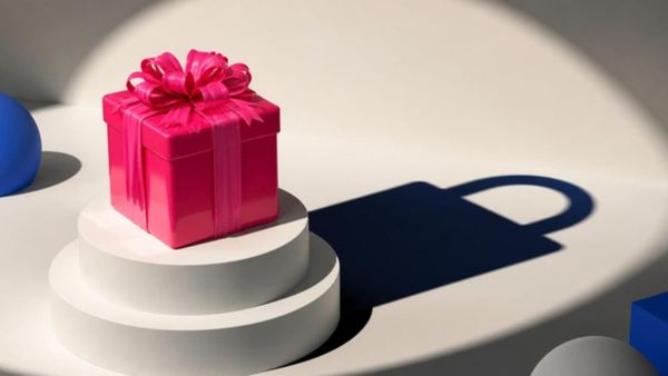 A pink gift-wrapped box on a pedestal casts a shadow shaped like a padlock.