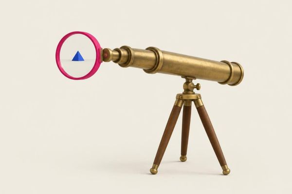 Brass telescope on a wooden tripod with a pink lens framing a small blue pyramid