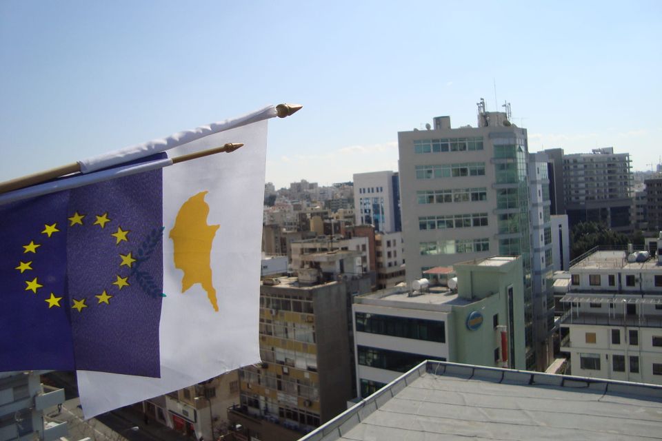 EU-Flaggen wehen vor der Skyline einer zyprischen Stadt