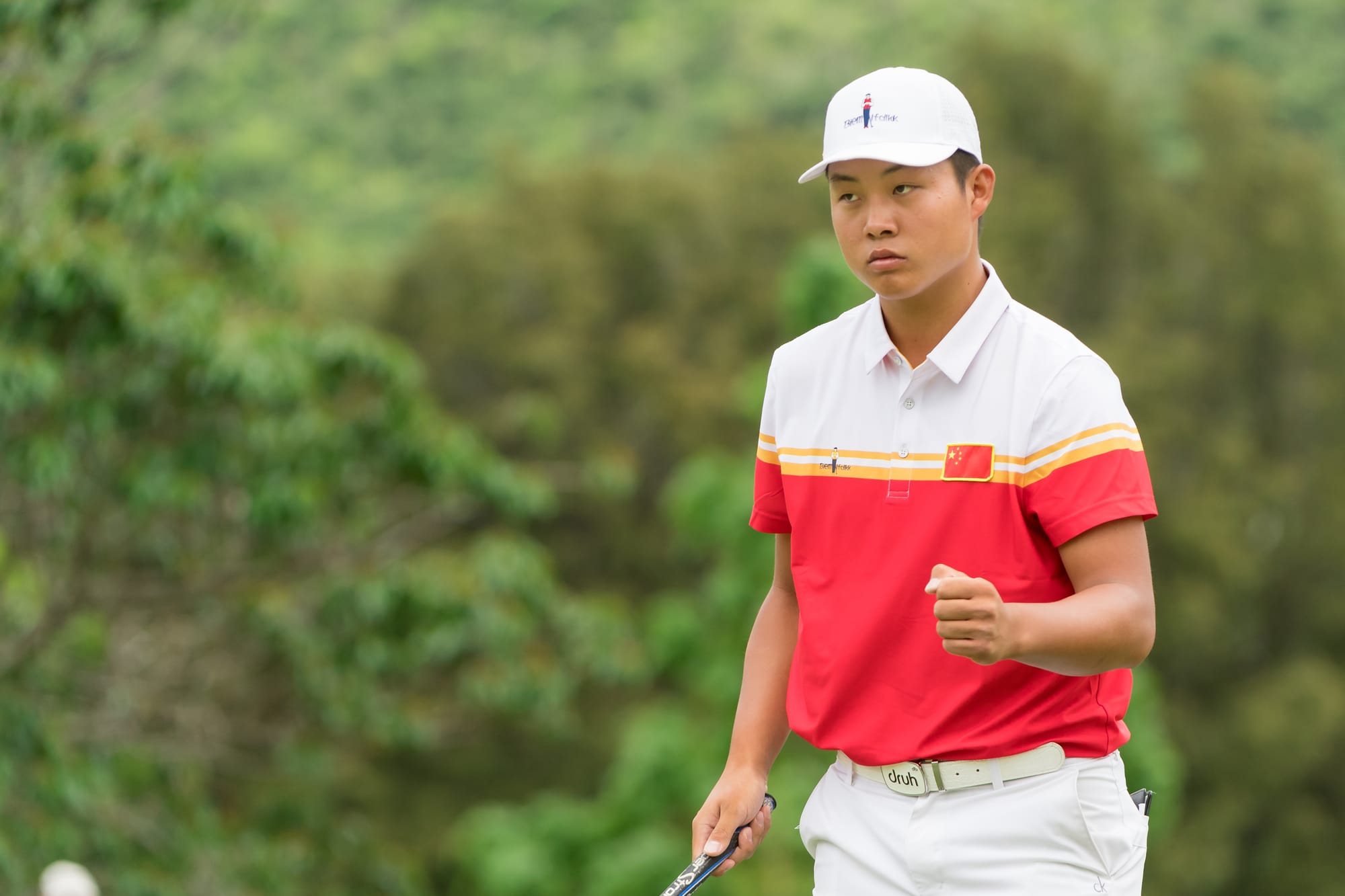 Lin Yuxin clenches his fist after holing a six-foot eagle putt on the final hole to secure victory.