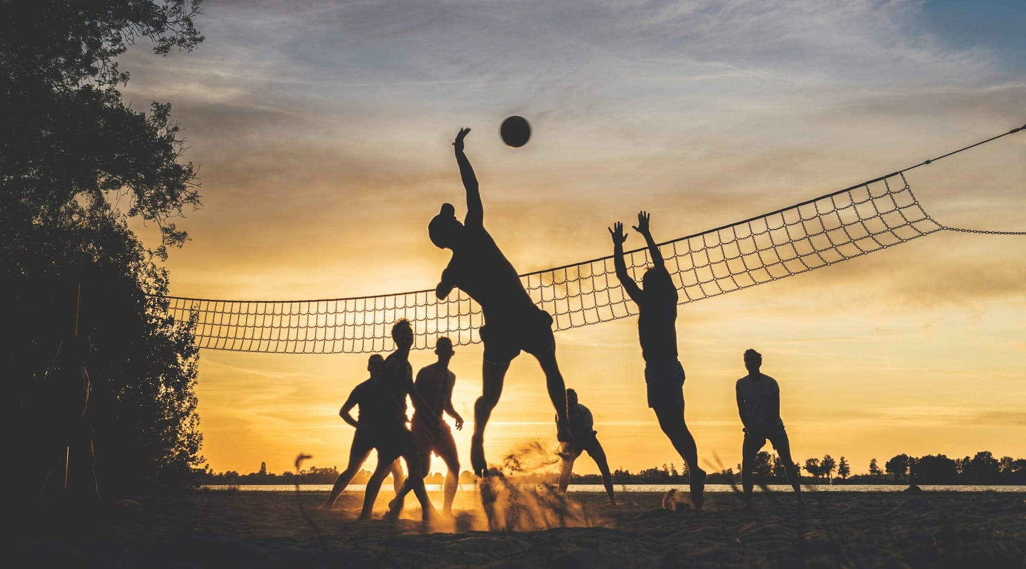 silhouettes playing beach volleyball at sunset