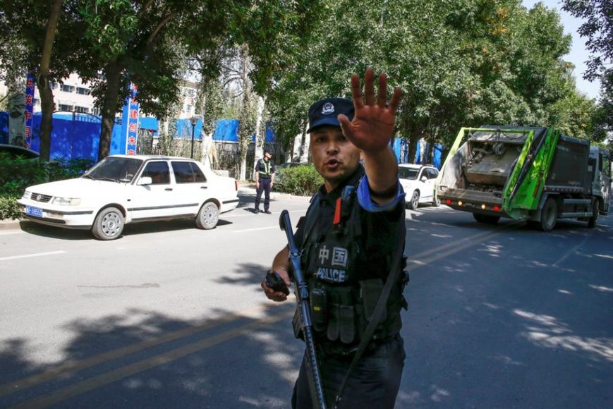 Un policier chinois ordonne à des reporters de ne pas avancer, à proximité d’un centre de détention au Xinjiang. (© Thomas Pe