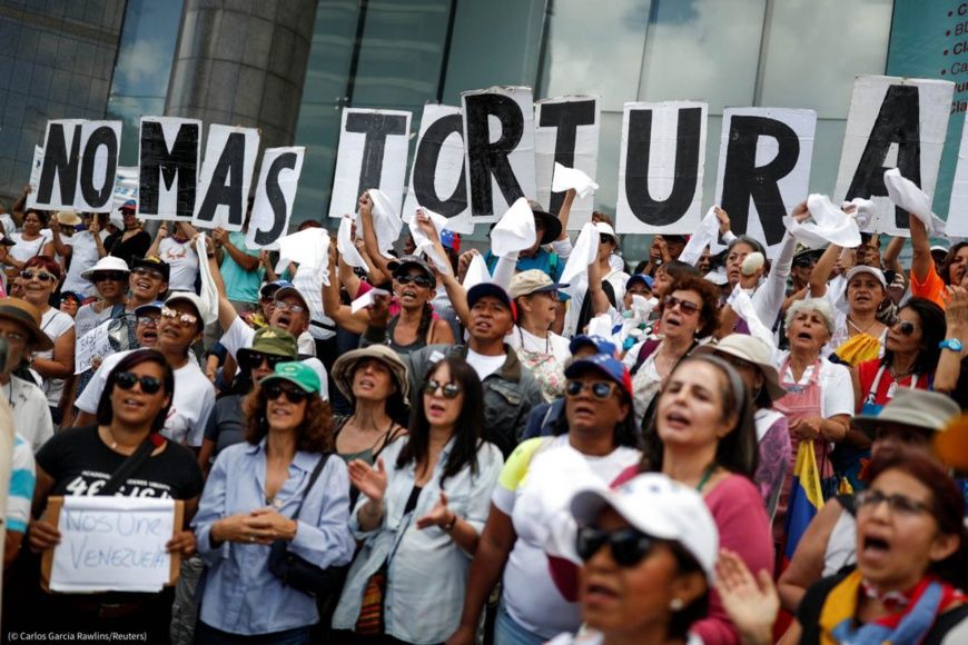 Le 5 juillet, des manifestants brandissent des pancartes qui forment le message « Fin à la torture » lors d’un rassemblement 