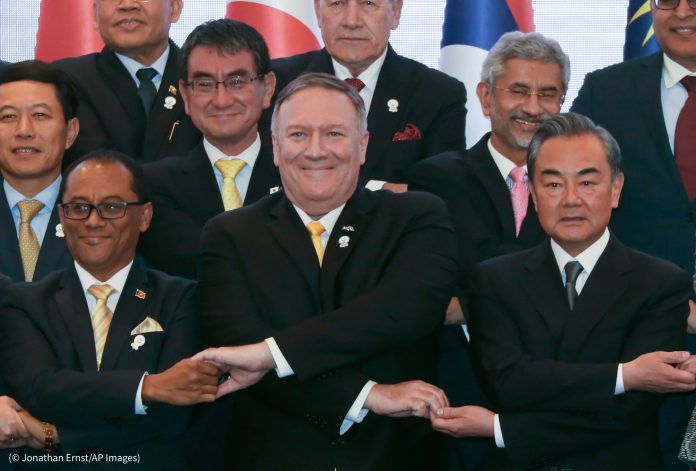 Le secrétaire d’État Mike Pompeo, au centre, se croise les bras pour serrer la main de ses homologues, comme le veut la tradi