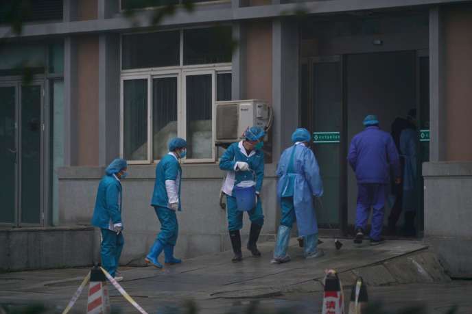 Des employés désinfectent l’entrée de l’hôpital de Wuhan, où des patients contaminés par le virus sont traités, le 22 janvier