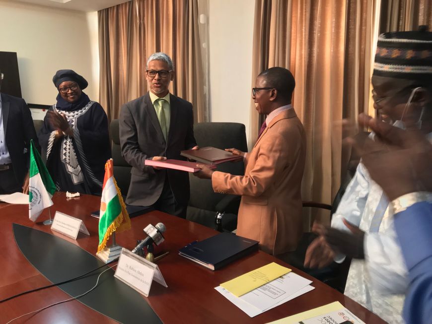 Échange de documents entre le responsable pays de la BAD et le ministre Nigérien du Plan après la signature des accords. © Af