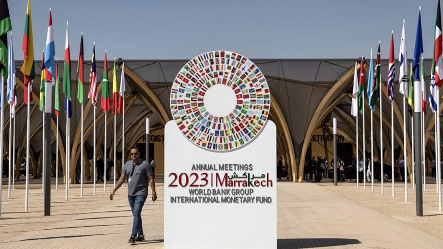 Un homme passe devant l'emblème des réunions annuelles 2023 du FMI et de la Banque mondiale à Marrakech. Photo : FADEL SENNA 