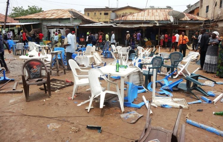 Des gens observent le site d'un précédent attentat à Sabon Gari, près de Kano (nord-est du Nigeria), le 30 juillet 2013 (Phot