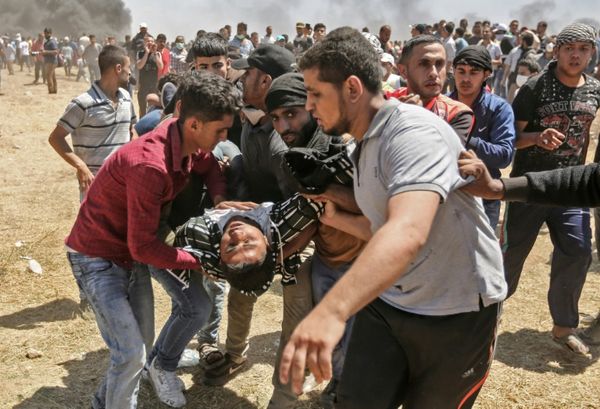 Un Palestinien blessé par des tirs israéliens est évacué par d'autres manifestants, le 14 mai 2018 dans la bande de Gaza, à l