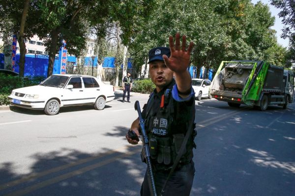 Un policier chinois ordonne à des reporters de ne pas avancer, à proximité d’un centre de détention au Xinjiang. (© Thomas Pe