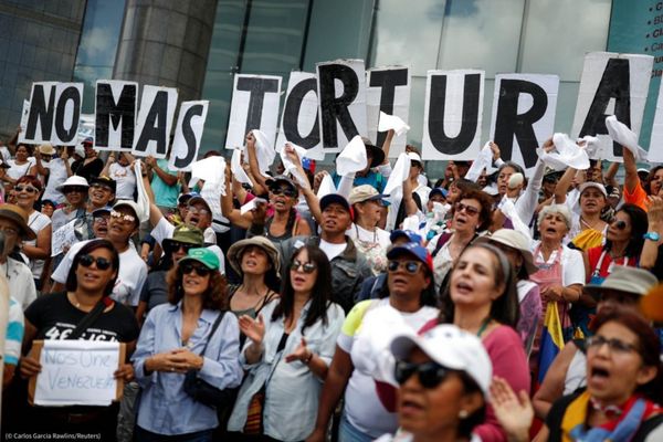 Le 5 juillet, des manifestants brandissent des pancartes qui forment le message « Fin à la torture » lors d’un rassemblement 