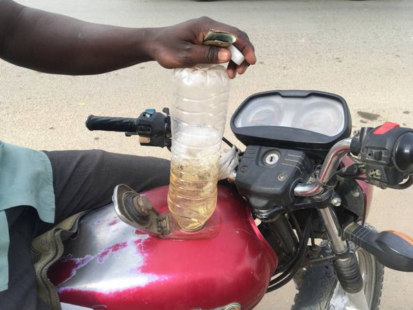 Un motocycliste vide une bouteille d'essence dans le réservoir de sa moto, le 29 avril 2023 à N'Djamena. © Mbaïnaissem Gédéon