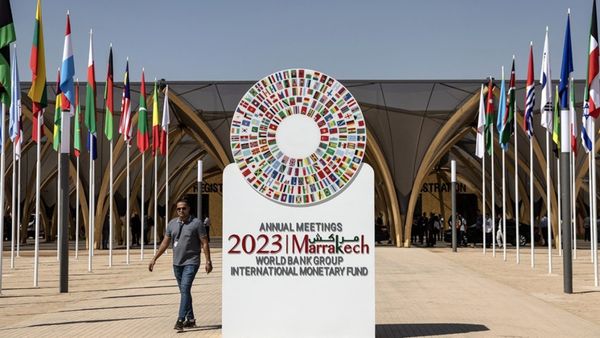 Un homme passe devant l'emblème des réunions annuelles 2023 du FMI et de la Banque mondiale à Marrakech. Photo : FADEL SENNA 