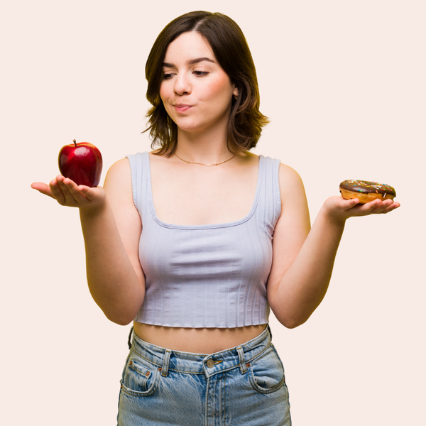 Woman holding an apple in one hand and a donut in the other. 