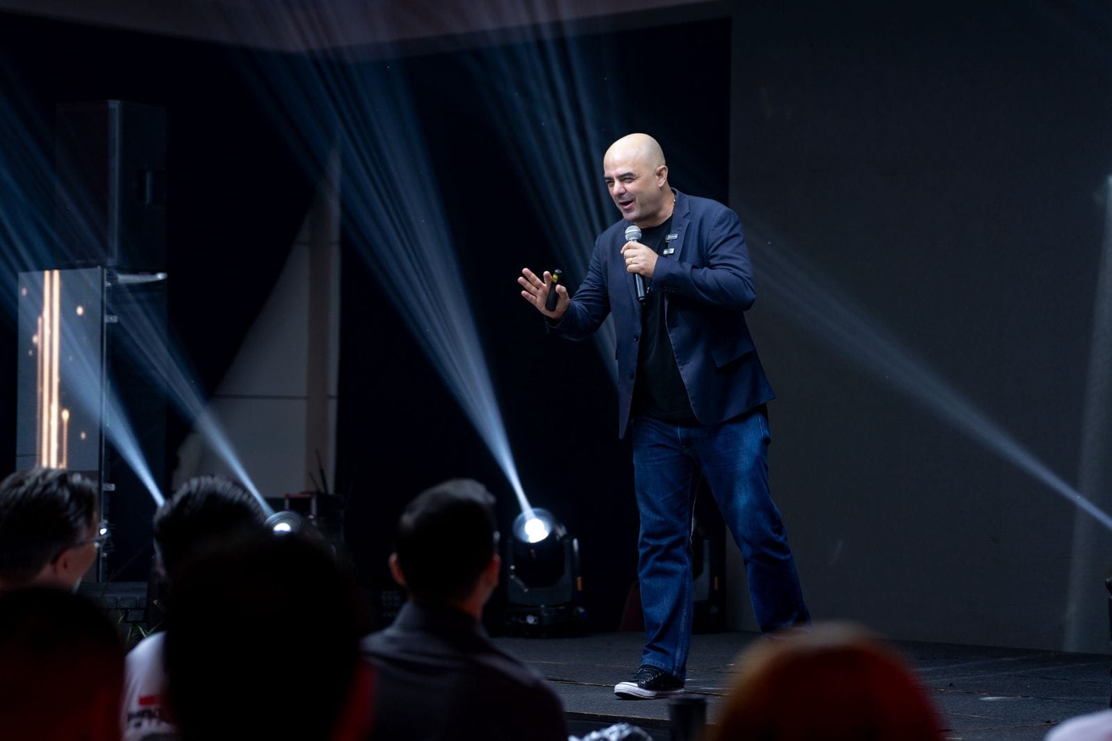 Foto do palestrante de vendas Leandro Branquinho em um palco falando ao microfone em uma convenção de vendas