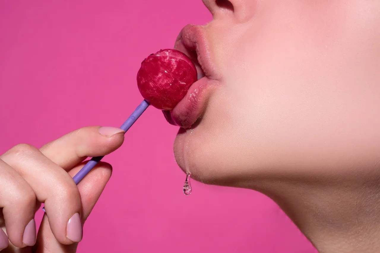 Close-up of lips licking a dripping lollipop and water dripping on her chin