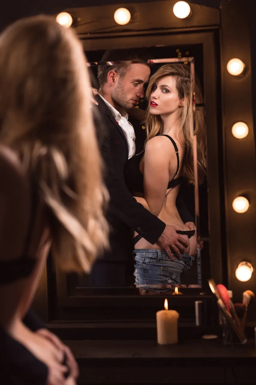 Couple seducing each other in front of a mirror with candlelight