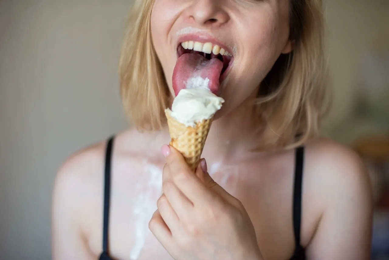 Slow, sensual licking of an ice cream cone, mirroring the teasing oral technique from base to tip that builds anticipation and drives him wild.