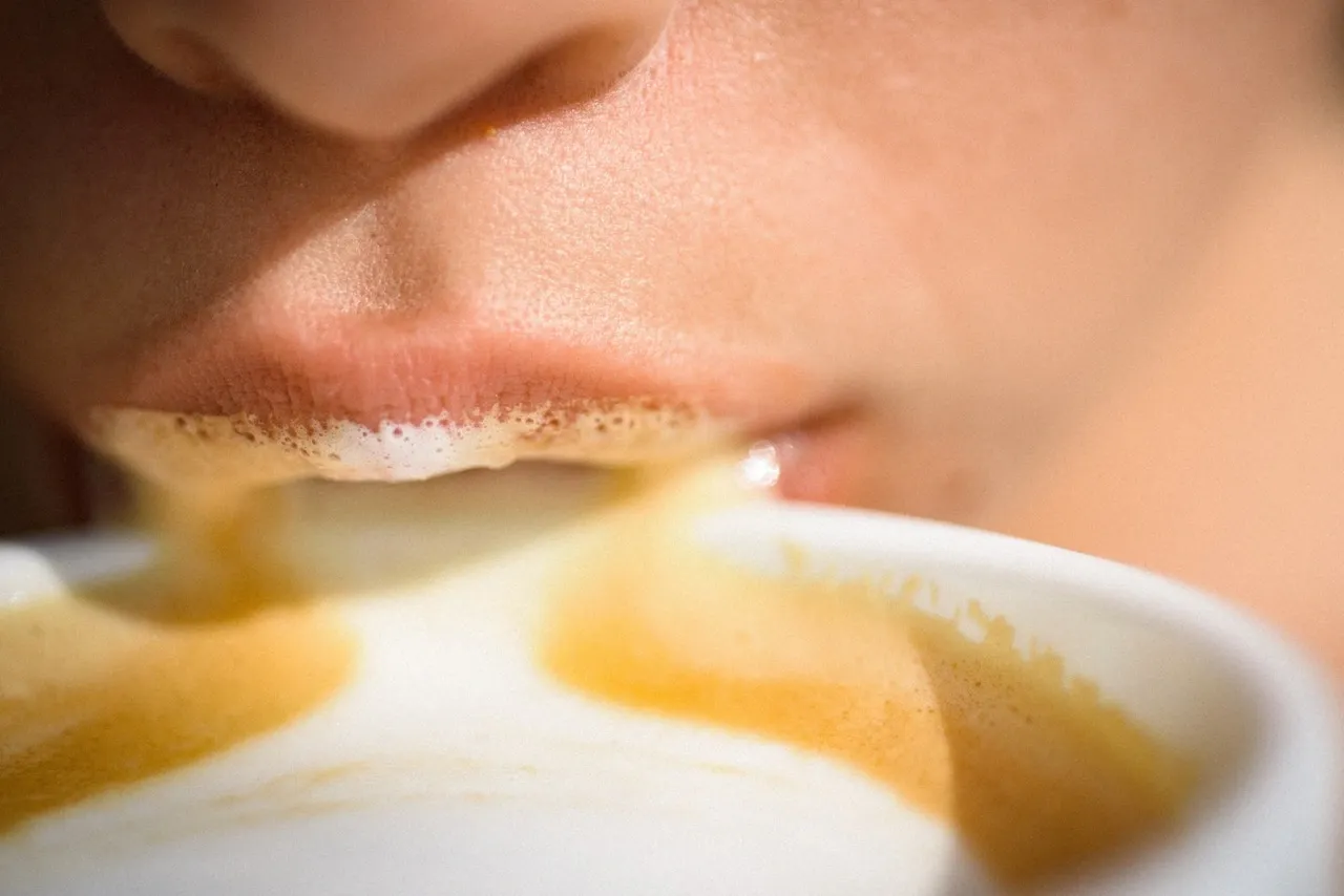 Close-up of lips sipping foamy coffee with creamy residue, symbolizing indulgence and morning intimacy.