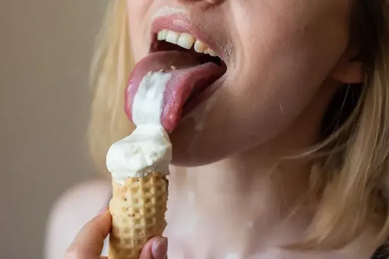 Playful woman licking melting ice cream with tongue out, teasing and sensual expression for boudoir inspiration