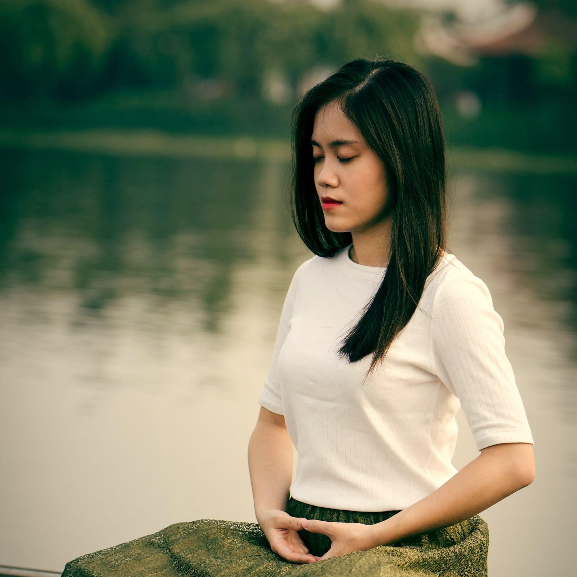 woman meditating on wooden dock during daytime