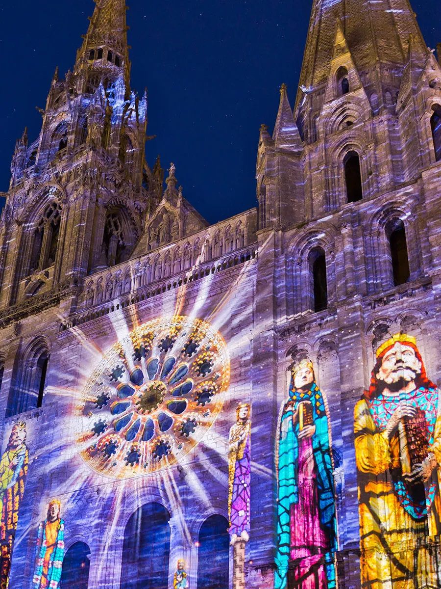 Spectacular radiant light rays on the exterior of a cathedral rose window during a light show at Chartres Cathedral.