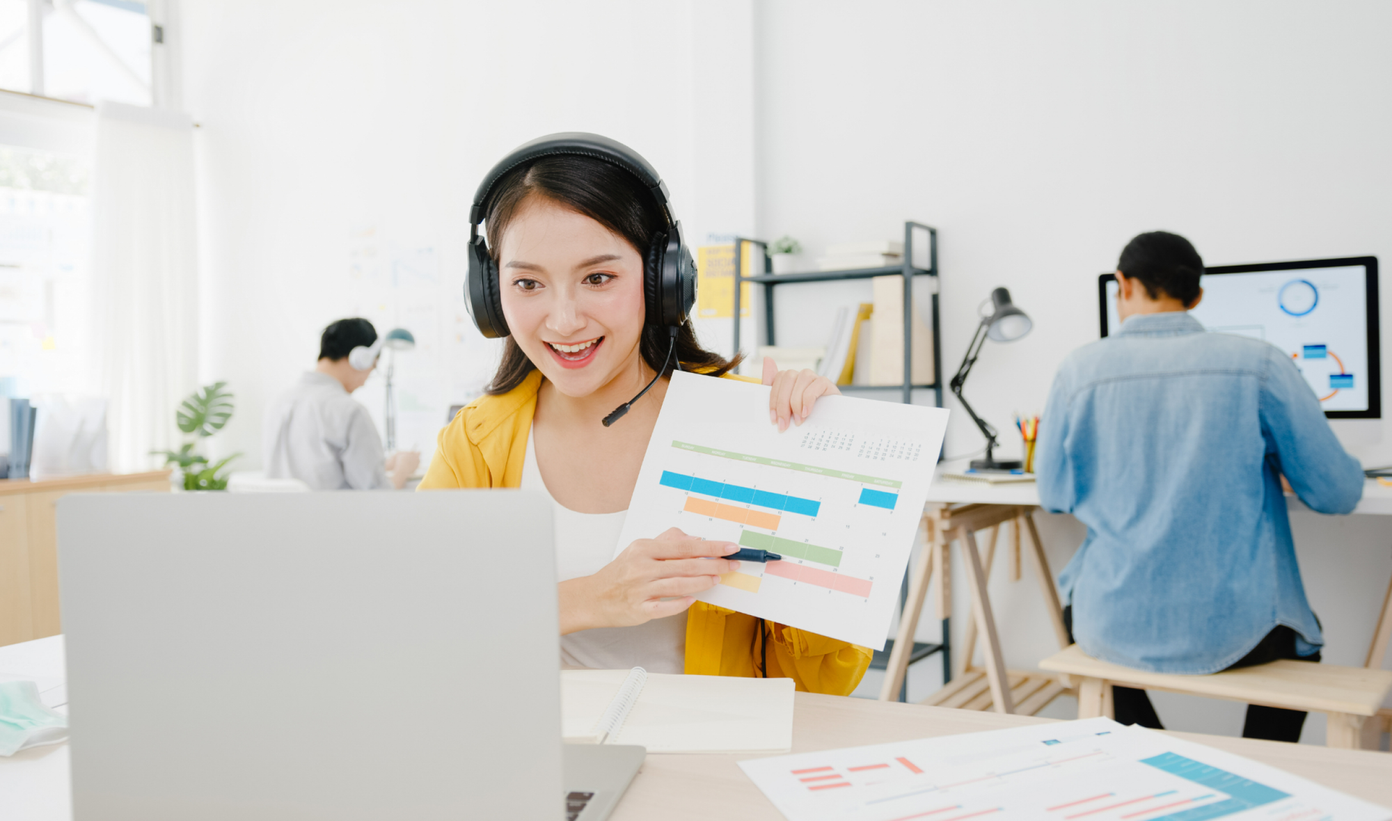 고객사와의 영상 채팅 도중 환한 얼굴로 손에 든 성과 차트를 설명하는 여성 CRM 마케터