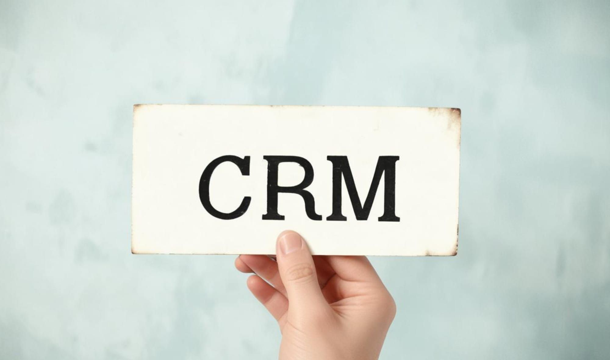 CRM이라는 단어가 쓰여진 빈티지 명함을 쥐고 있는 손. 