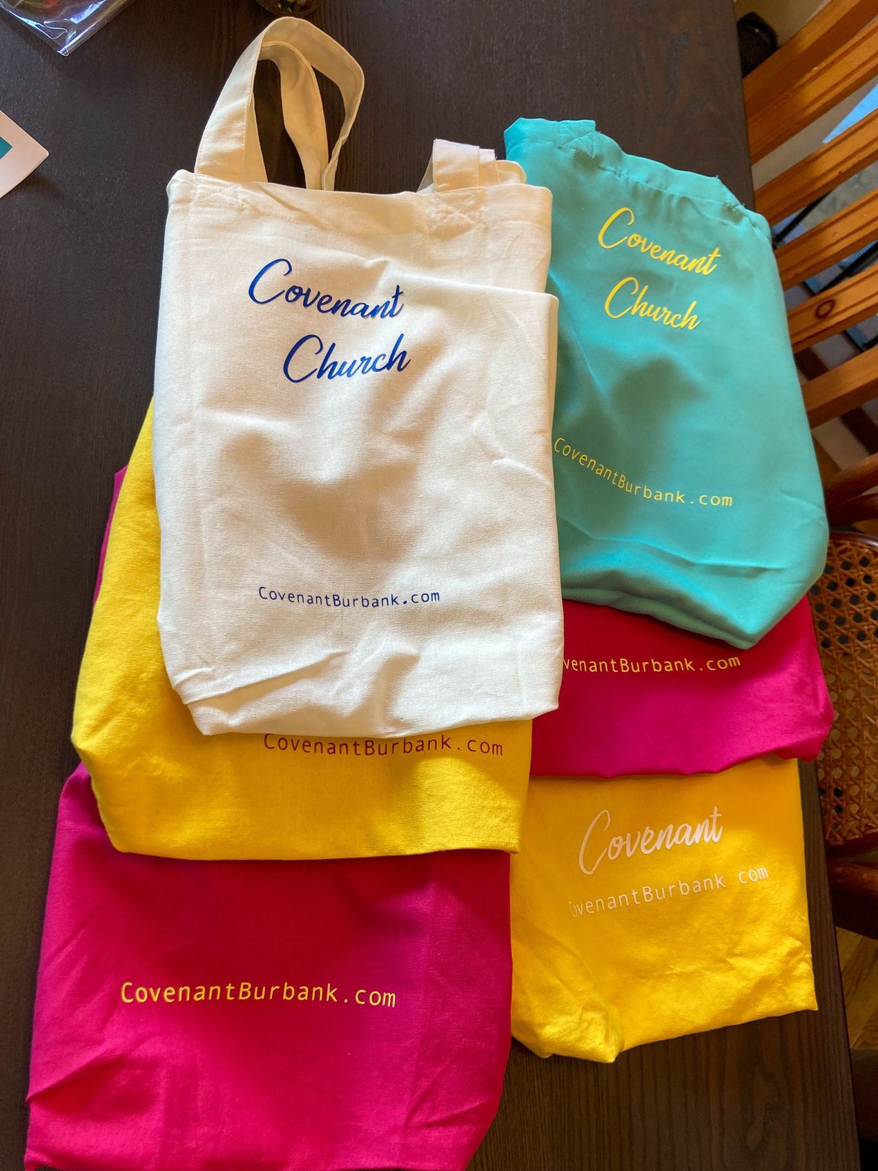 Colorful bags on a table that have been personalized to say "Covenant Church" and "CovenantBurbank.com"