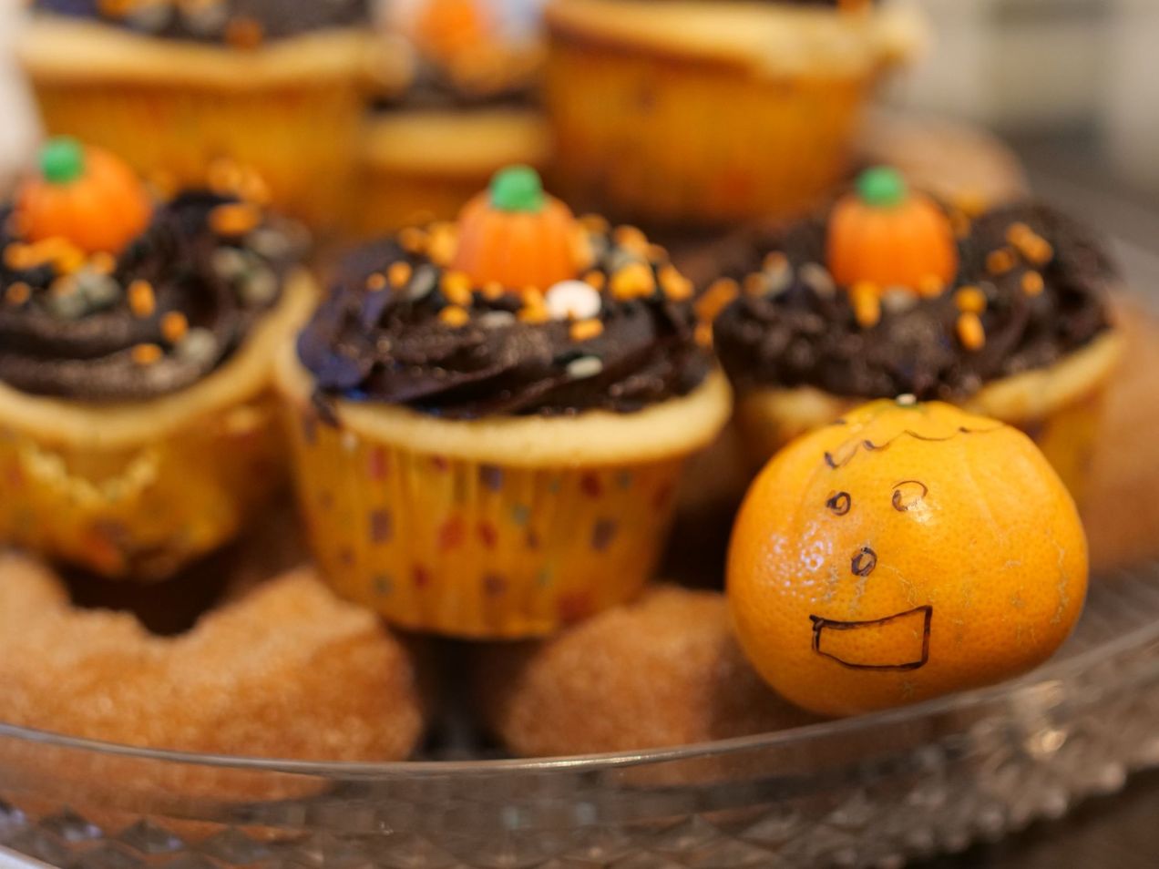 An orange that looks like a carved pumpkin, cupcakes, and doughnuts on a plate at the Covenant Church meeting on October 30.