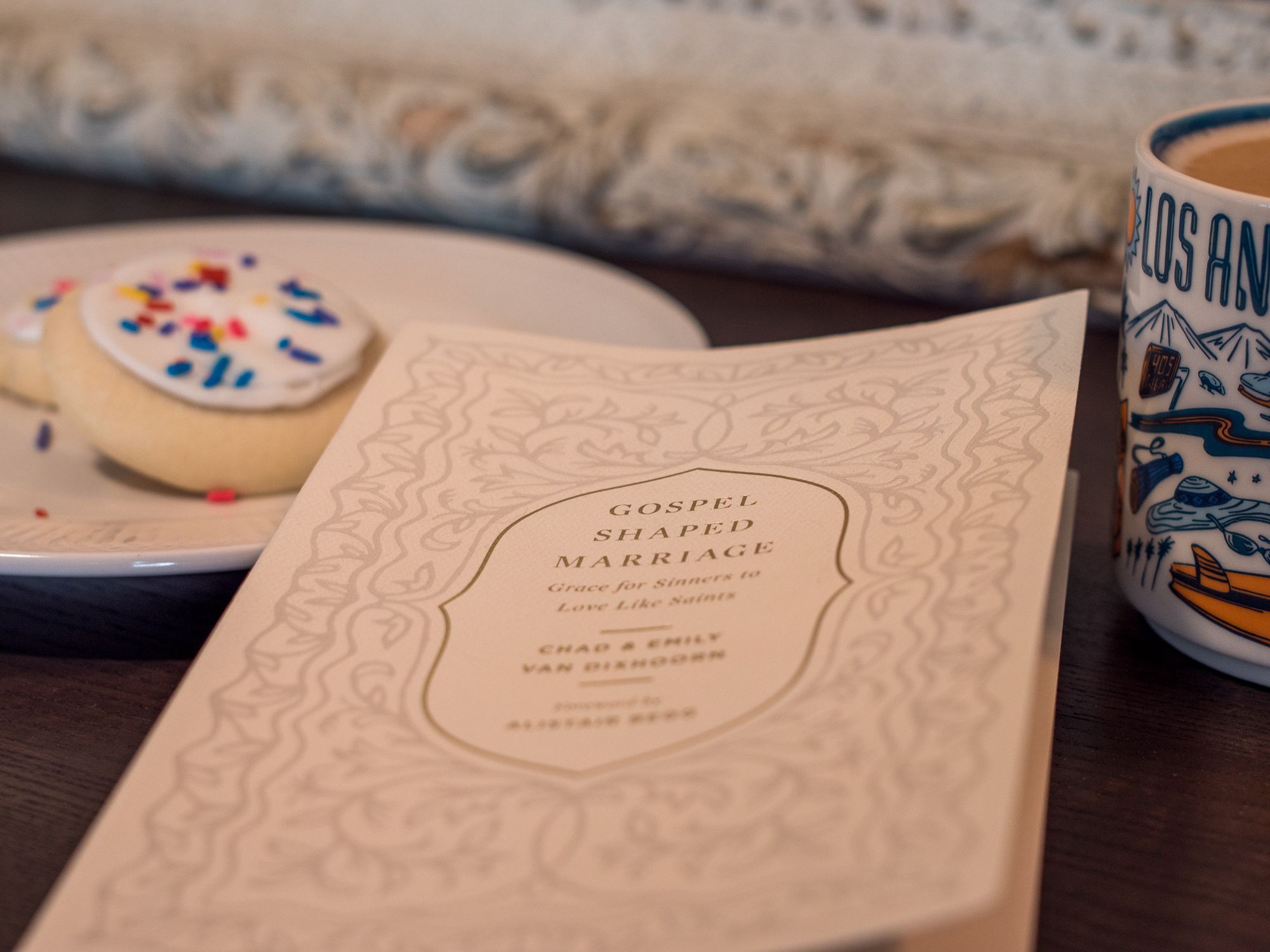 Photo of the book "Gospel-Shaped Marriage," a plate of cookies, and a Los Angeles coffee mug.