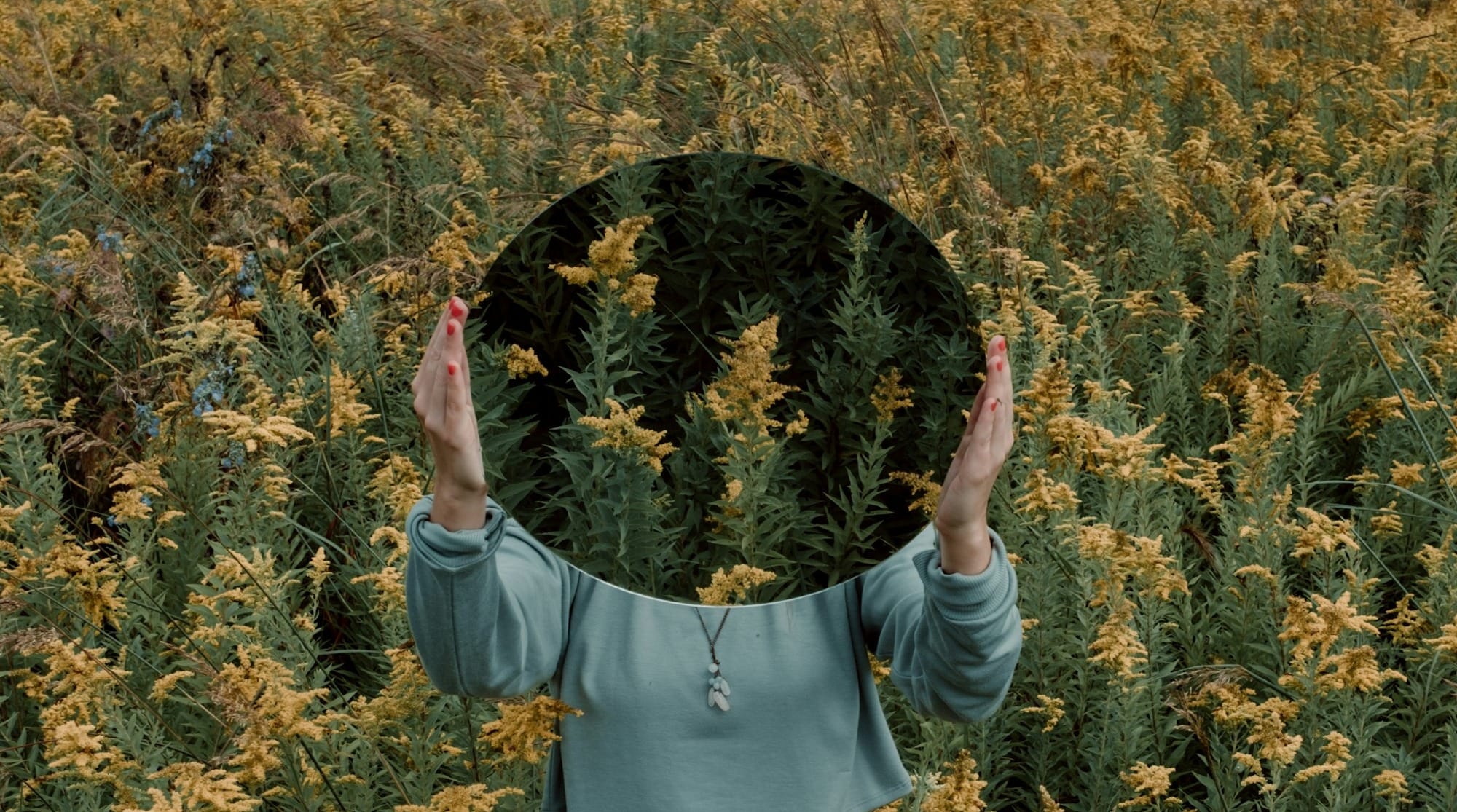 standing woman surrounded by yellow flower field during daytime
