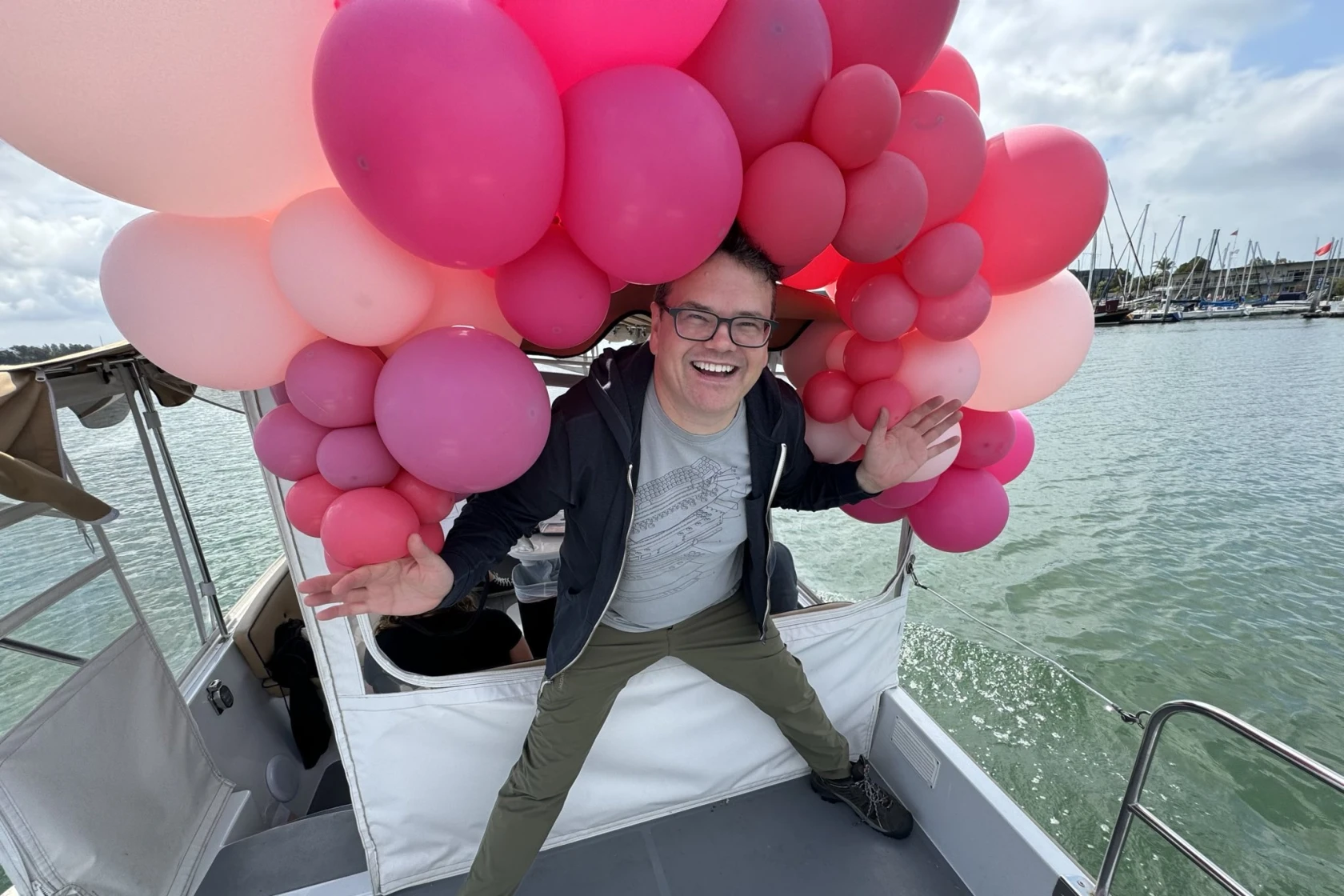 Jeff Atwood with a halo of pink balloons standing on an electric boat