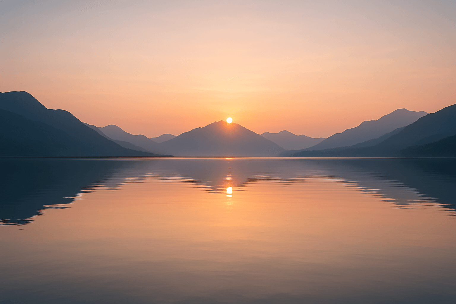 A serene lake at sunset, with majestic mountains silhouetted in the background.