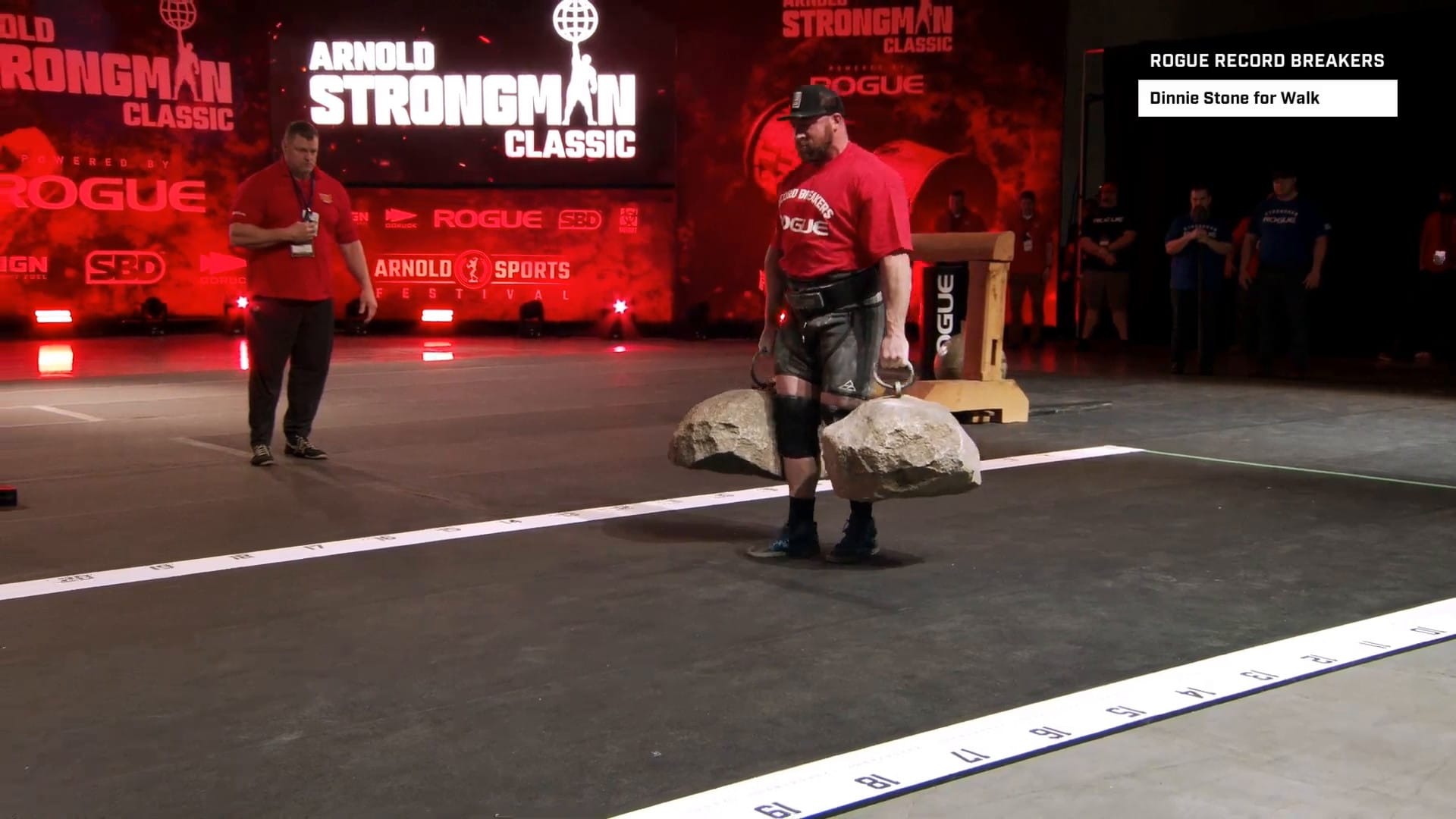 Kevin Faires holds two heavy stones in his hands, side-by-side, on the platform of the Rogue Record Breakers in 2023.